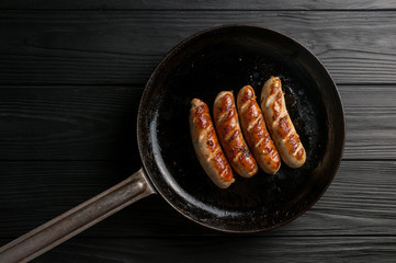 Black pan with delicious sausages on the grill on the kitchen table.