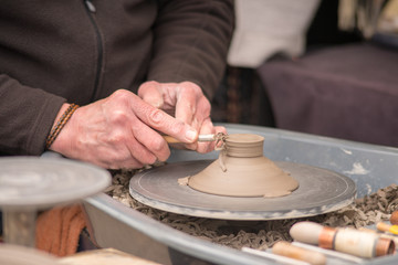 man working with clay pot before it is fired on potters wheel in traditional workshop