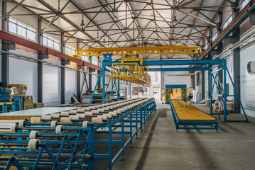 Insulation sandwich panel production line. Machine tools, roller conveyor and gantry crane in workshop