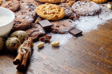 Baked cookies with chocolate and peanuts and ingredients on the old wooden table.