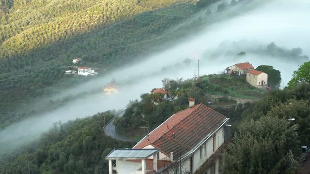 Early foggy morning in the Alpine town. Fog from the mountains makes its way along the medieval streets. Perinaldo, Liguria, Italy.
