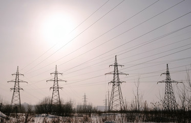 High-voltage towers, transmission line in winter city background.