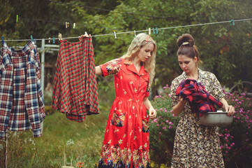Naklejka premium young women hanging clothes after washing in the courtyard in the open air, female life and fun