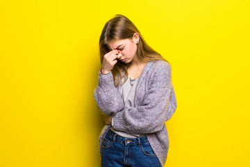 Young beautiful woman with headache isolated on yellow background.