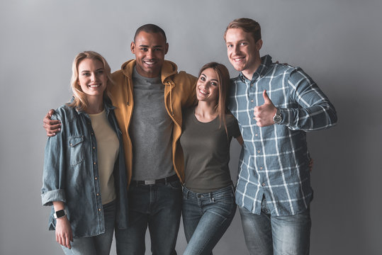 Portrait of young men and women posing and hugging. They looking at camera with smile. Isolated on background