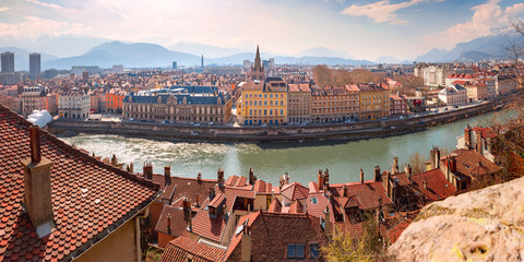 Scenic panoramic aerial view of the banks of the Isere river, bridge, and Old Town with French Alps on the background, Grenoble, France