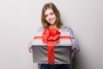 Fototapeta premium Adorable teenage girl looking at box pointed on camera with present isolated on white