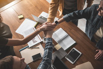 Top view of male and female people holding hands in conjunction above working table