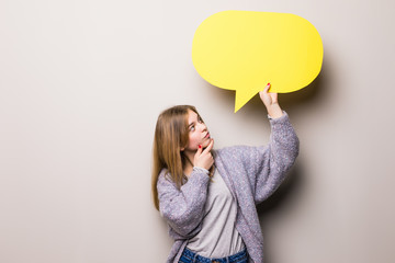 Fototapeta premium Young beautiful greaming girl holding a green bubble for text, isolated on a gray background