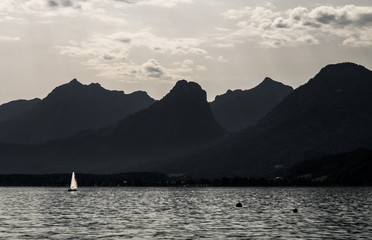 Un velero navegando en un lago bajo las montañas, en la cordillera de los Alpes.  Wolfgangsee, Austria