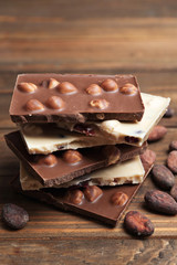 Yummy chocolate pieces with hazelnuts on wooden table