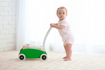 Cute baby with toy walker indoors