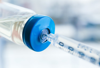 Vial with vaccine and syringe on blurred background