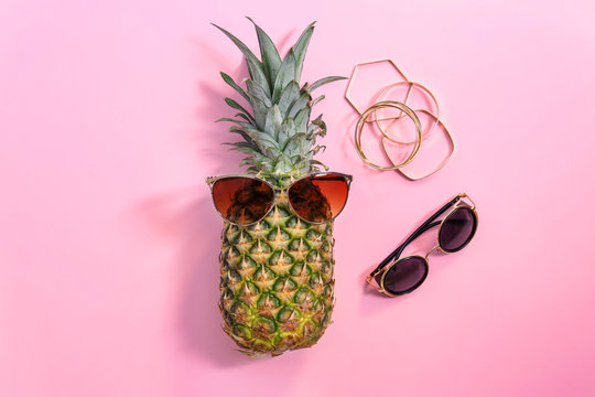 Fresh ripe pineapple with sunglasses on color background, top view