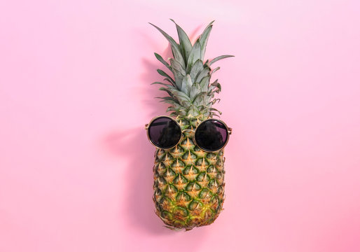 Fresh ripe pineapple with sunglasses on color background, top view