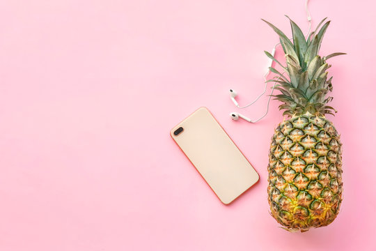 Fresh ripe pineapple with earphones and mobile phone on color background, top view