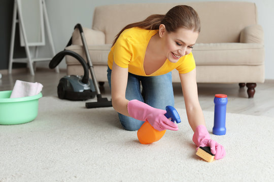 Young Woman Cleaning Carpet At Home