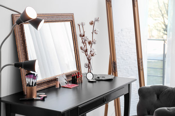 Decorative cosmetics and tools on dressing table near mirror in makeup room