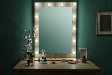 Decorative cosmetics and tools on dressing table near mirror in makeup room