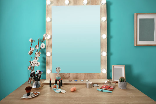 Decorative cosmetics and tools on dressing table near mirror in makeup room