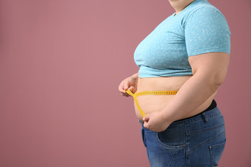 Overweight woman with measuring tape on color background