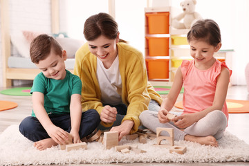 Fototapeta premium Nanny and little children playing at home