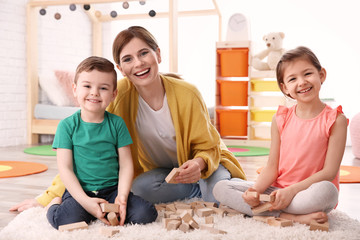 Fototapeta premium Nanny and little children playing at home