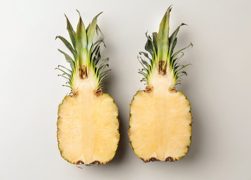 Fresh pineapple halves on light background, top view