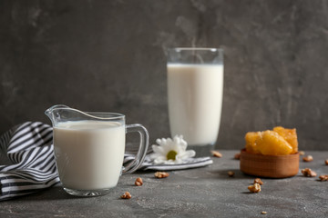 Jug with milk and nuts on grey table