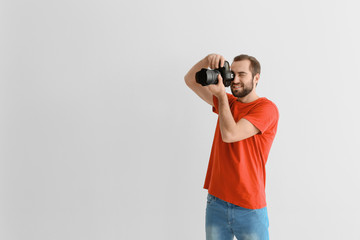Young photographer with professional camera on white background