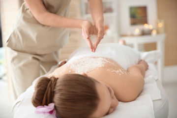 Obraz na płótnie Canvas Beautiful young woman having massage with body scrub in spa salon
