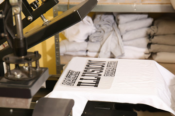 Young man printing on t-shirt at workshop
