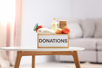 Donation box with food products on table indoors