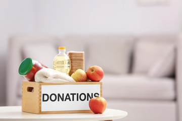 Donation box with food products on table indoors