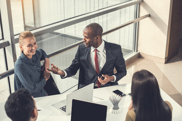 Top view happy colleagues taking during labor. They sitting at table in modern office. Glad employers during labor concept
