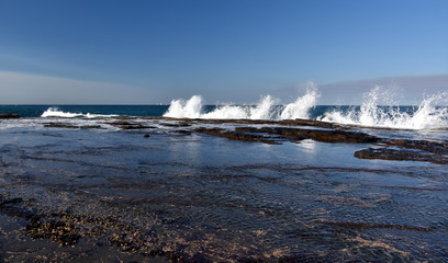 Splash in the shape of a wave and water flow at Narrabeen rock shelf at high tide