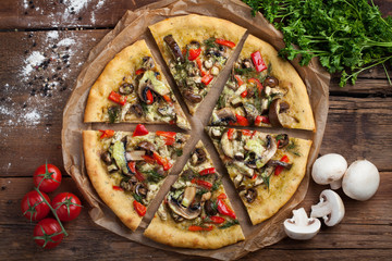 Home-made vegan pizza with tomatoes, bell peppers, mushrooms and fennel on an old wooden table. Top...