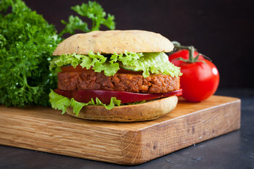 Fresh vegan Burger with tomato, cucumber, lettuce and vegan cutlet on wooden Board
