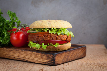 Fresh vegan Burger with tomato, cucumber, lettuce and vegan cutlet on wooden Board