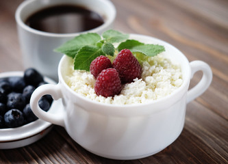 Russian cottage cheese with berry and mint, blueberries and coffee on wooden table.