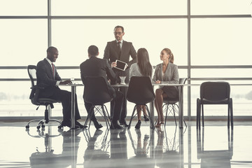 Concentrated bearded male presenting screen of electronic tablet for partners. Occupation concept