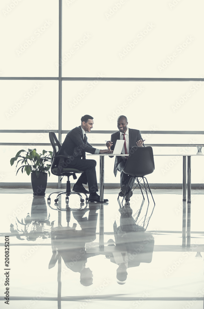Poster full length satisfied employer talking with beaming businessman. they looking at notebook computer i
