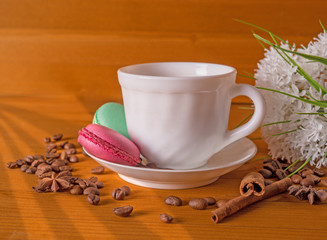 Cup with coffee, cakes on a plate, white flowers, grains of coffee and cinnamon on a wooden...