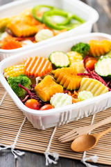 Vegetables salad in a plastic box with wooden spoon and fork, healthy food