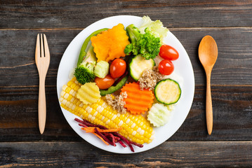 Vegetables salad with spoon and fork on wooden background, healthy eating, top view
