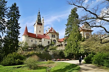 Fototapeta premium Zdjęcia redakcyjne słynnego romantycznego zamku Pruhonice, Czechy, Europa, stojący na wzgórzu, ogród, słoneczny wiosenny dzień, błękitne niebo, zielona trawa, drzewa, gałęzie, ścieżka, ludzie
