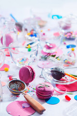 Glass tea cups in the morning light. Birthday party concept with sprinkles, confetti, candies, macaroons and birthday candles. Colorful celebration concept
