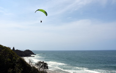 Paraglider flying over the sea with blue water and mountains in bright sunny day. Aerial view of paraglider in Port Macquarie. Pacific coast at Port Macquarie, in New South Wales Australia.