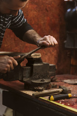 Man works in carpentry workshop. He files excess wood with an ax.