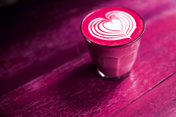 Cup of beetroot latte or pink matcha on the painted table background